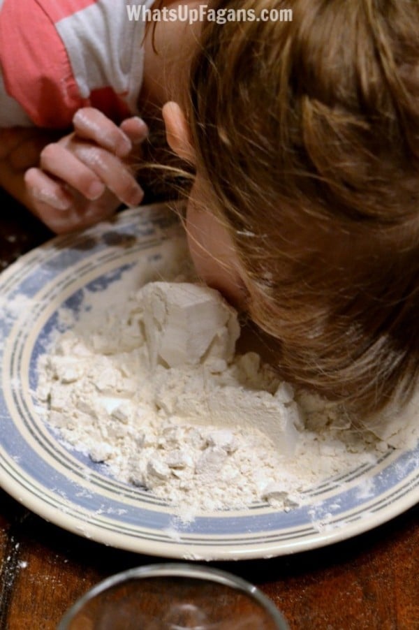 a kid with their face in a plate of flour