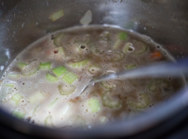 vegetables and broth in an instant pot with a spoon in it