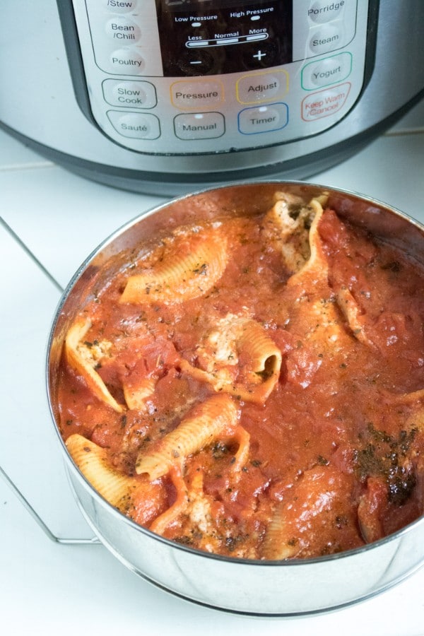pasta shells stuffed with sausage and cheese covered in sauce in a pan with an instant pot in the background