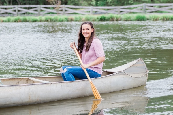 a girl in a canoe with a paddle on the water