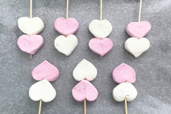 heart shaped marshmallows on wooden skewers on wax paper