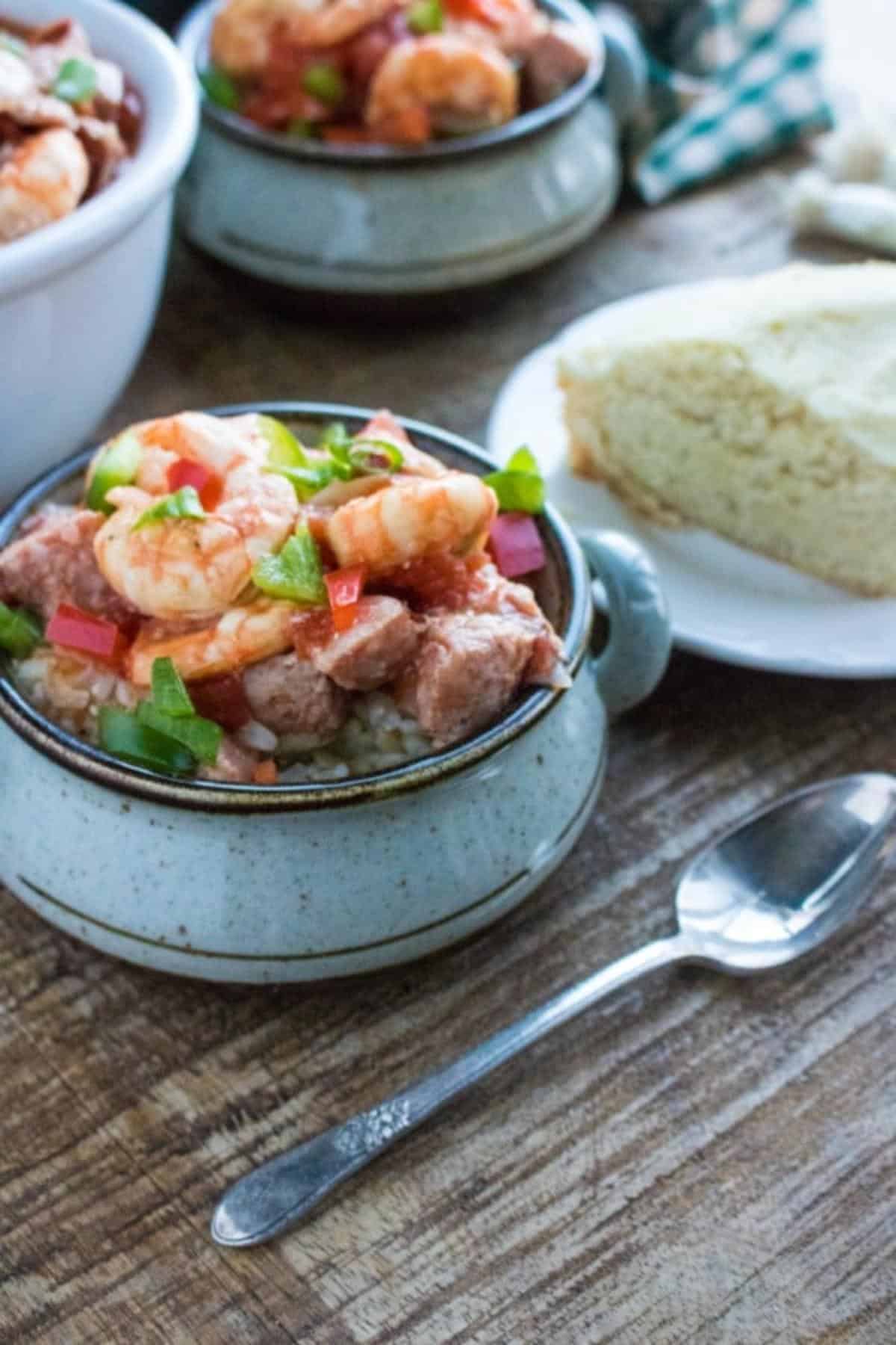 A collage of bowls filled with sausage & shrimp gumbo on a table next to a spoon and a slice of bread on a plate.