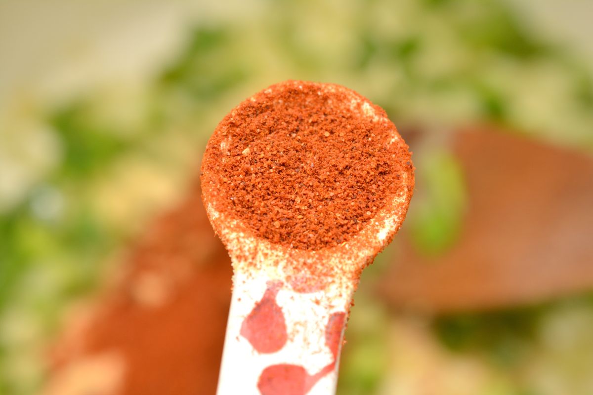 a measuring spoon with chili powder in it.