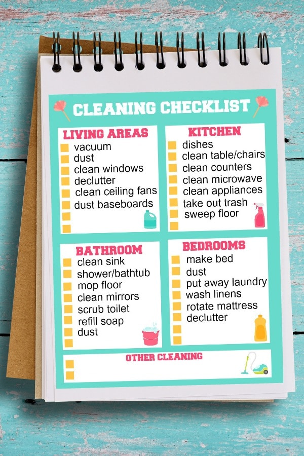 free printable cleaning checklist in a notebook on a green wood background