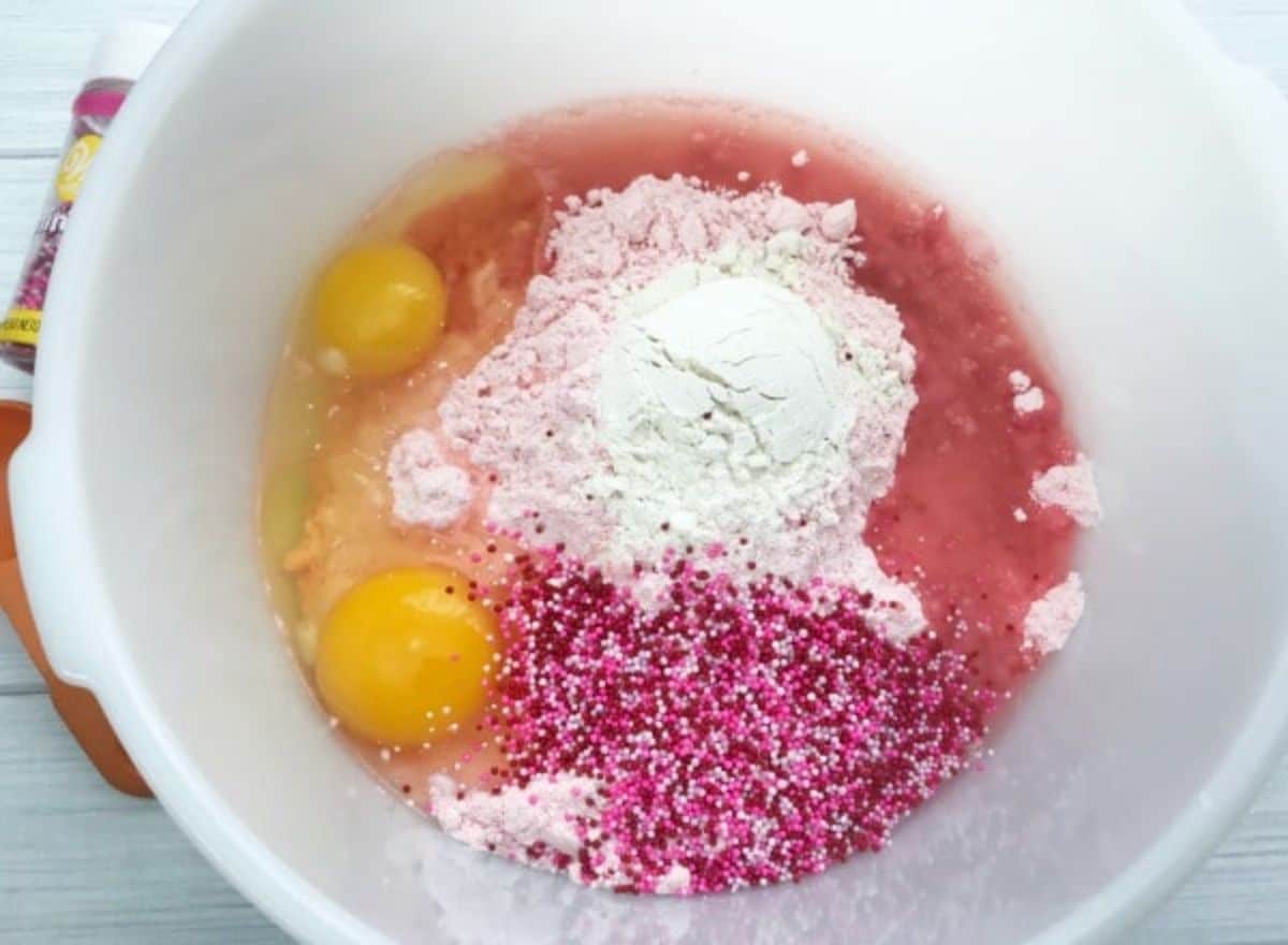 strawberry cake mix, vegetable oil, eggs and flour in a mixing bowl.