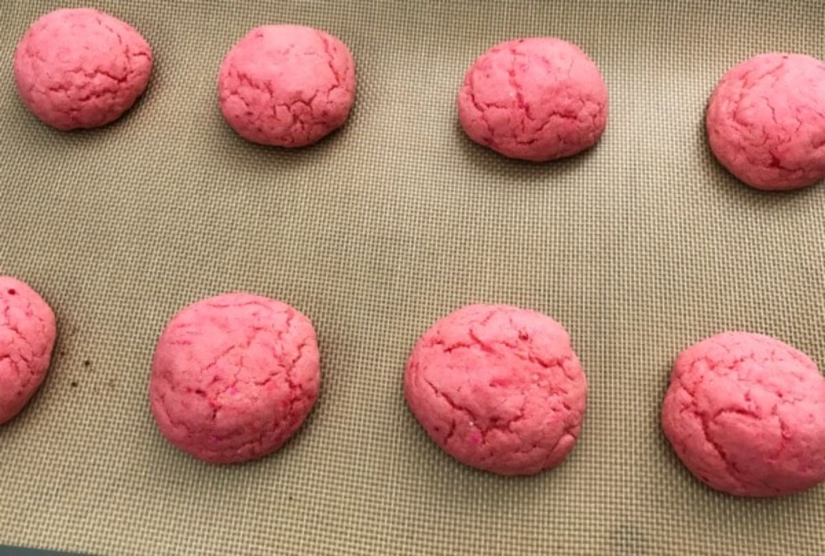 baked pink cookies on a baking mat.