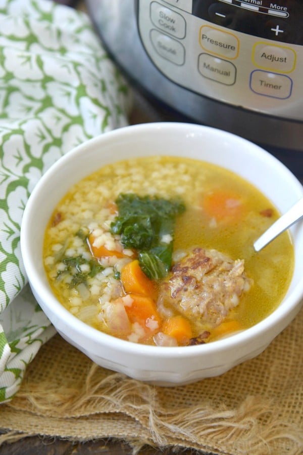 italian wedding soup in a white bowl with a spoon in it with a green cloth and an instant pot in the background