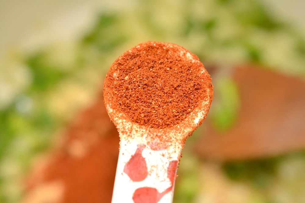 a measuring spoon with chili powder in it