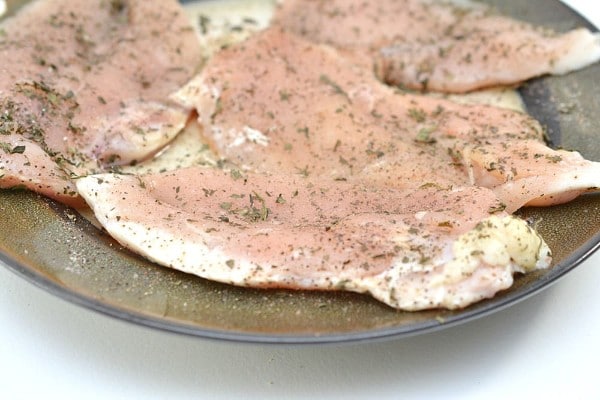 raw chicken breasts on a plate coated with seasoning