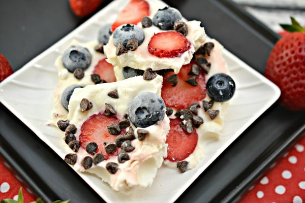 Chocolate Berry Frozen Yogurt Bark on a black tray with strawberries around it