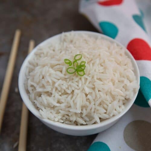 An instant pot bowl of white rice with chopsticks on a polka dot cloth.
