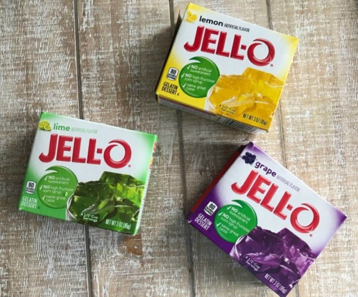 a box of purple, yellow, green jello for Mardi Gras on a wood background.