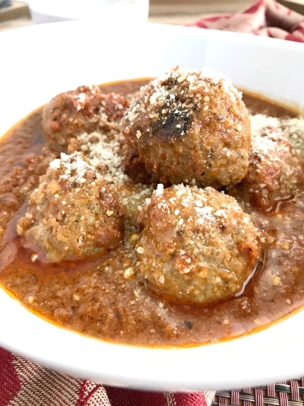 meatballs and sauce topped with parmesan cheese in a white bowl