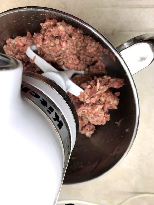 a kitchen aid mixer mixing meat in a mixing bowl