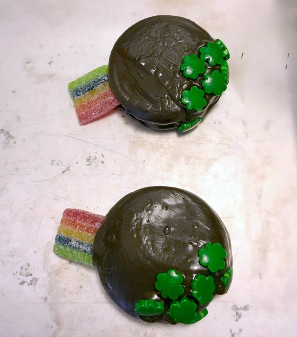 Oreo cookies covered in chocolate, topped with green shamrock candies, and a rainbow candy