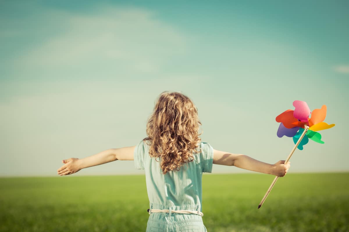 little girl with arms spread looking at the sky