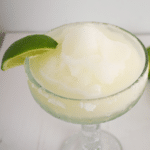 A classic frozen margarita recipe served in a salt-rimmed glass and garnished with a wedge of lime.