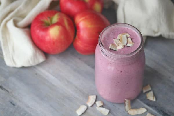cranberry apple smoothie in a glass jar with apples in the background