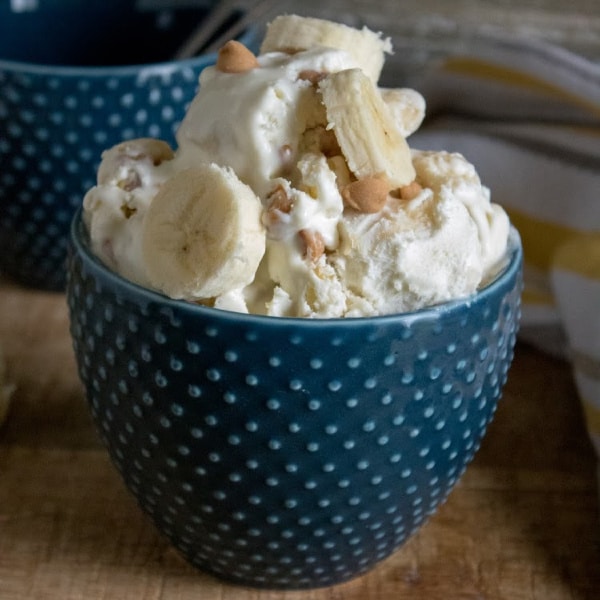 homemade peanut butter banana ice cream in a blue bowl with an empty blue bowl in the background