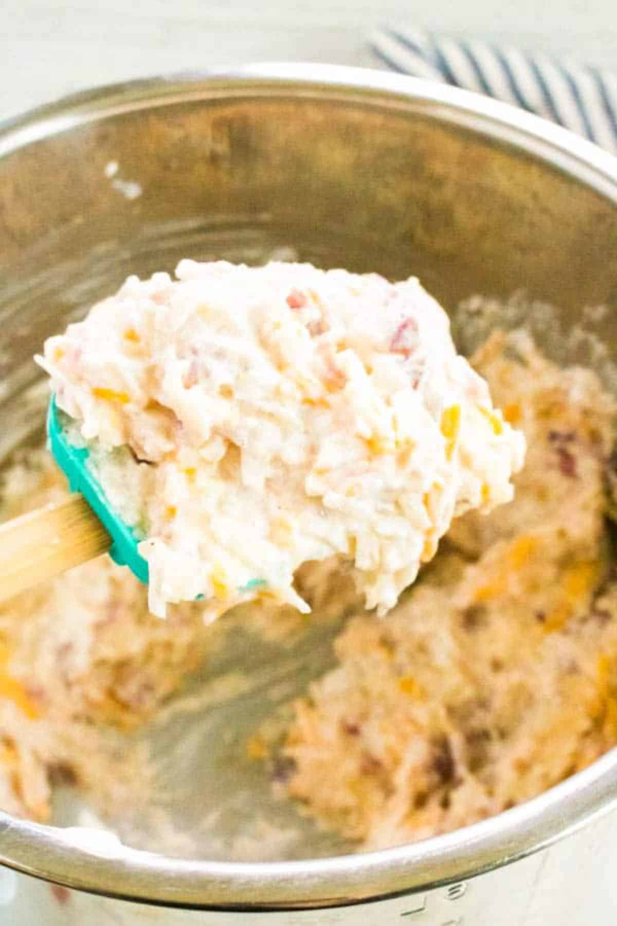 a spatula with a scoop of Cheesy Potatoes from an instant pot.