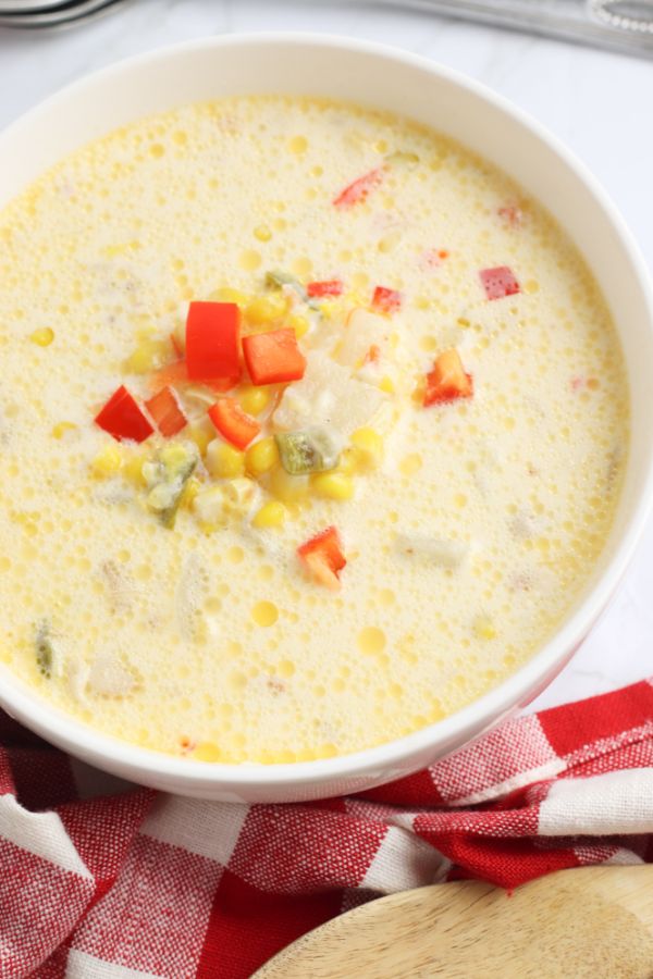 bowl of corn chowder with corn kernels and chopped red bell pepper garnish 