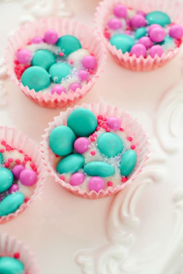 pink and green candy in paper muffin cups on a white plate