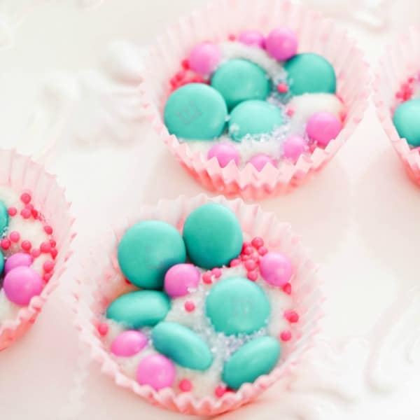 pink and green candy in paper muffin cups on a white plate