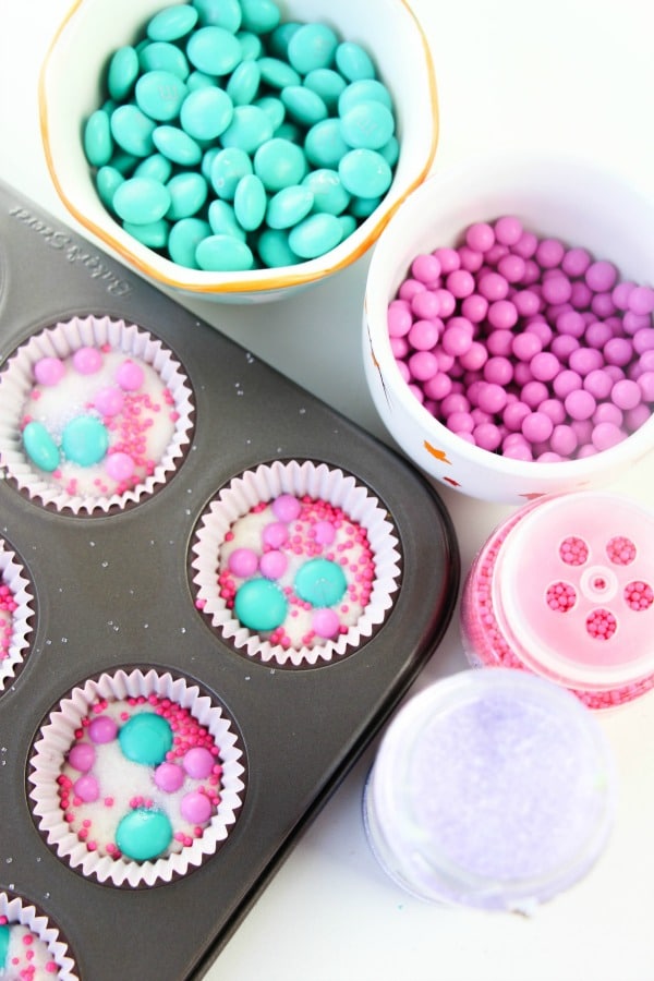 pink and green candy in cups and also in paper lined muffin cups in a muffin pan