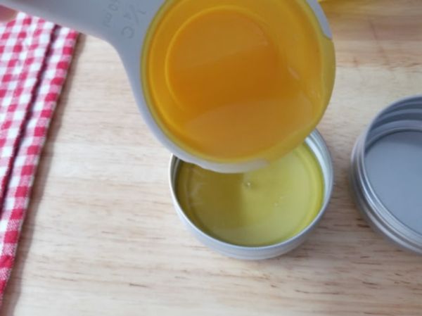 oil from a measuring cup being poured into a container of essential oil itch relief cream