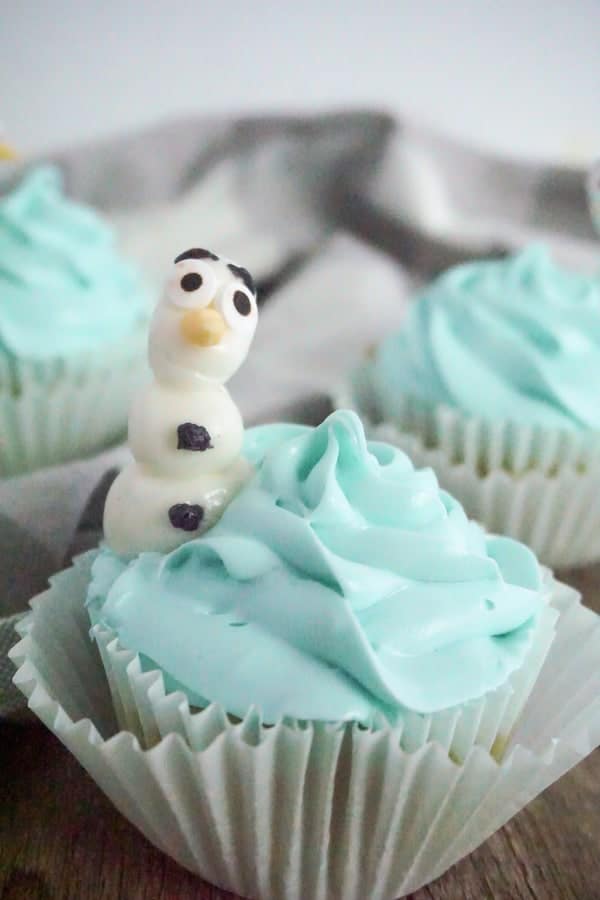close-up of cupcakes with olaf on them on a wood table with a grey and white linen in the background