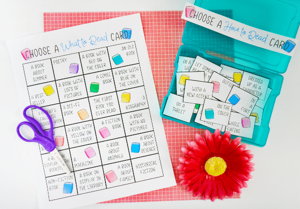 printable summer reading challenge next to a blue plastic box filled with cut up cards from the printable next to a red flower on a red checkered background