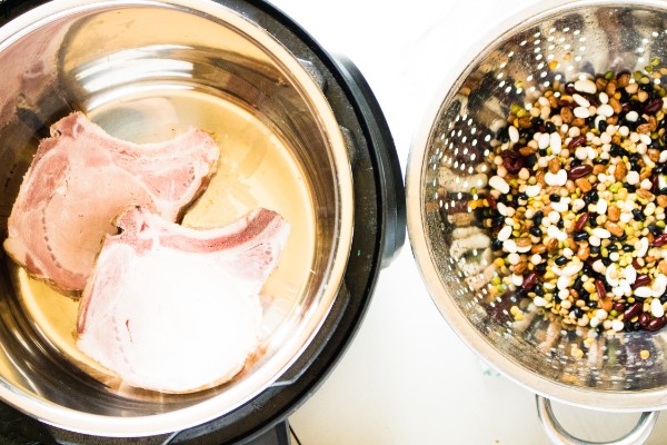 pork chops in an instant pot next to a metal colander filled with beans
