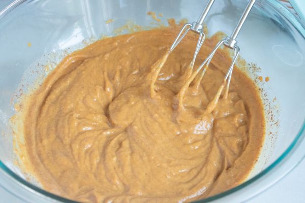 pumpkin mousse being mixed in a glass mixing bowl with beaters