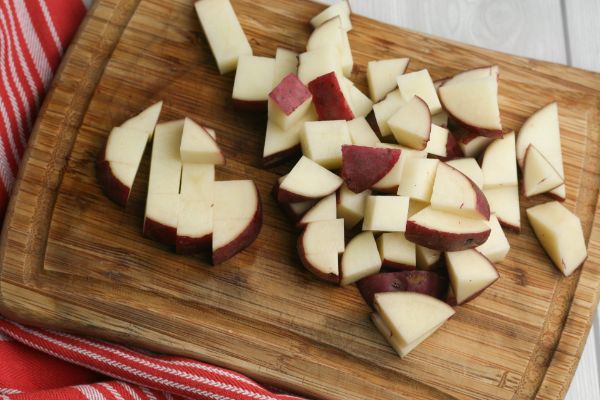 cut potatoes on a cutting board on a white table and red linen