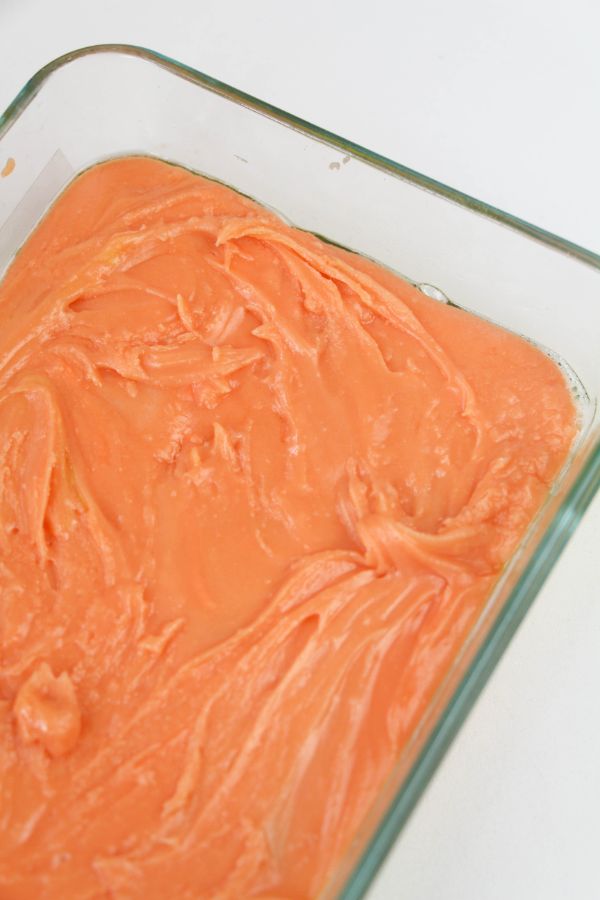 orange candy melted in a glass baking dish on a white background