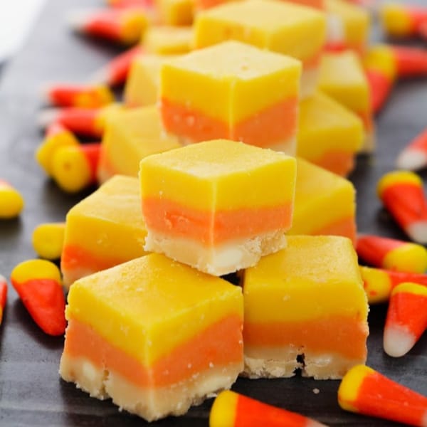 yellow, orange, and white Halloween fudge surrounded by candy corn on a wooden board
