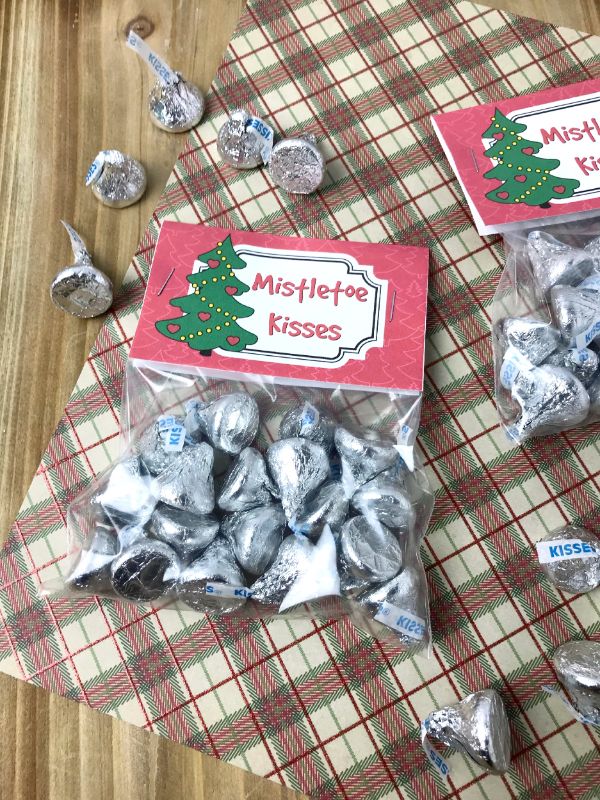 plastic bags filled with hershey kisses with a label on them that reads mistletoe kisses on a checked brown linen on a brown table
