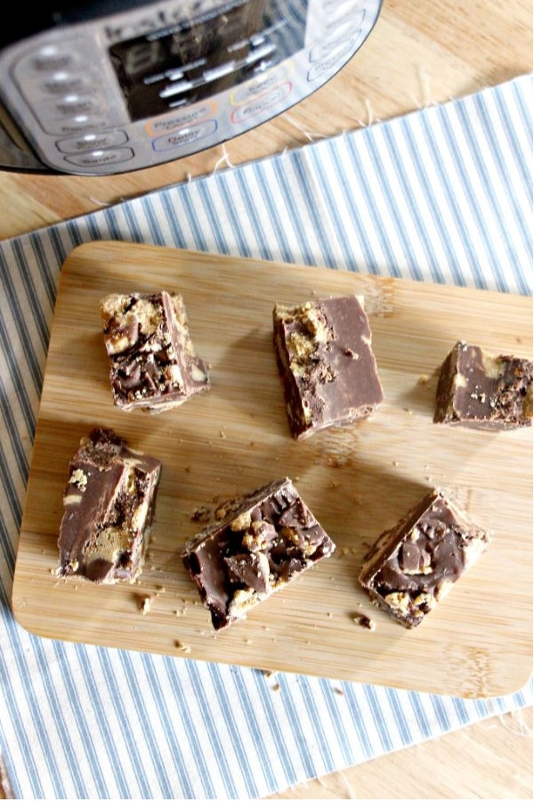 Reese's Peanut Butter Fudge on a brown cutting board on a blue and white striped linen with an Instant Pot in the background