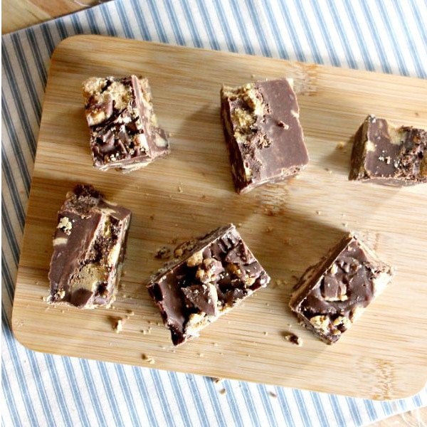 Reese's Peanut Butter Fudge on a brown cutting board on a blue and white striped linen