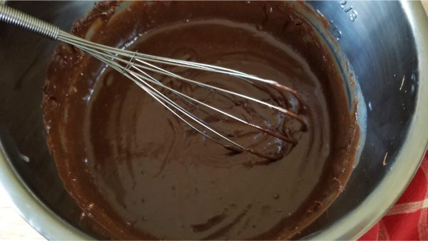 a whisk in the instant pot that's filled with the melted chocolate fudge mixture
