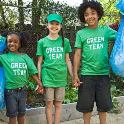 3 young children wearing green shirts and volunteering