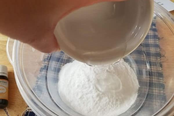 adding soap to a bowl of baking soda to make DIY bathroom cleaner