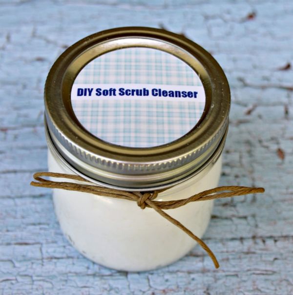 a glass jar with the label on the lid DIY Soft Scrub Cleanser on a table