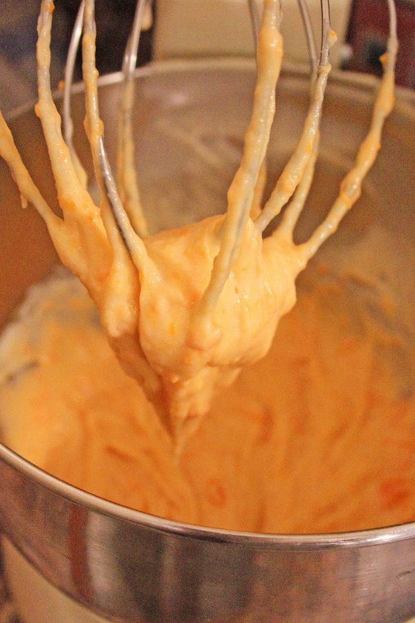 a whisk with cupcake batter on it above a mixing bowl full of sweet potato cupcake batter