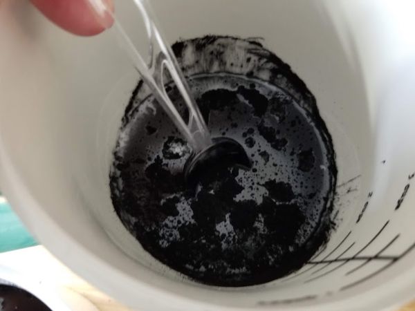 charcoal powder being stirred into a bowl of soap base