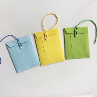 blue, yellow, green miniature envelopes with string closing the envelopes