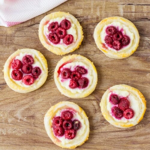mini raspberry tarts on wooden surface