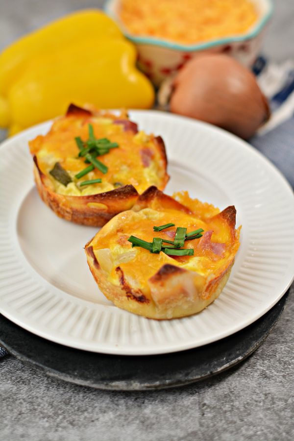 Muffin Tin Western Omelets on a white plate with a pepper, onion and cheese in the background