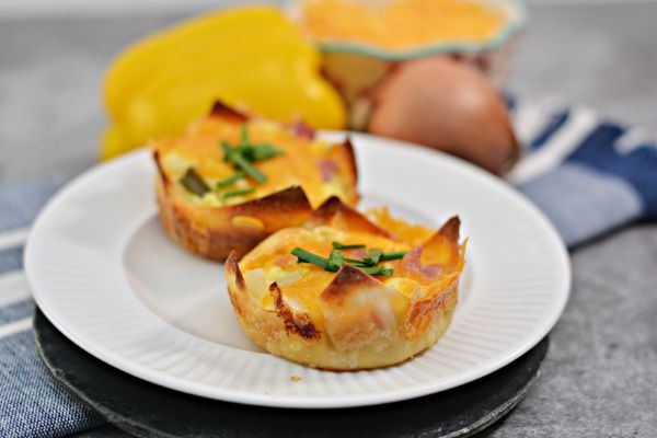Muffin Tin Western Omelets on a white plate with a pepper, onion and cheese in the background