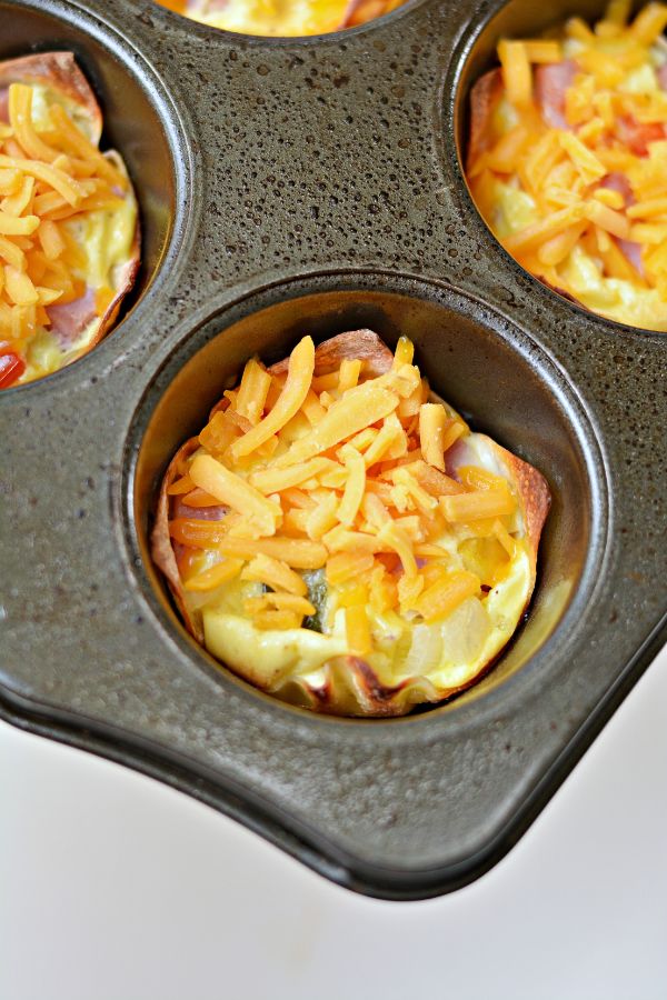 wonton wrappers, ham and veggies, eggs, topped with shredded cheese in a muffin tin